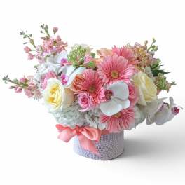 Pink and white mixed flower arrangement in a textured round box with a ribbon