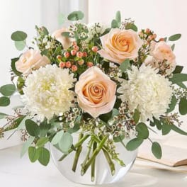 Peach roses and white chrysanthemums in a clear glass vase
