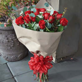 Bouquet of red roses wrapped in beige paper with a red ribbon
