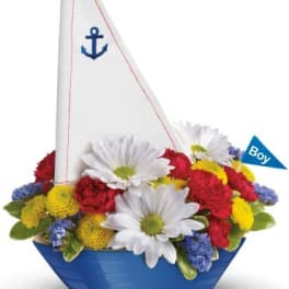Sailboat-shaped flower arrangement with white daisies in a blue container