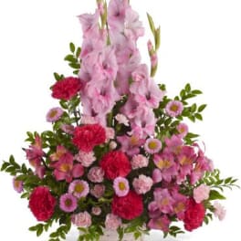 Pink and red floral arrangement in a white basket