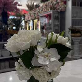 White floral arrangement in a clear square vase