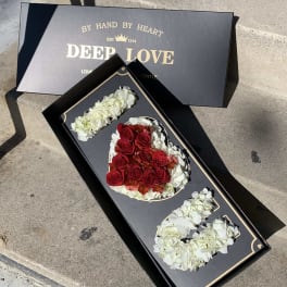 Boxed floral arrangement spelling "I LOVE U" with red and white flowers
