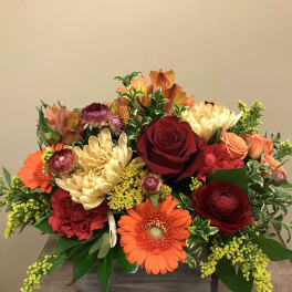Mixed bouquet with red roses, orange gerberas, and cream chrysanthemums in a wooden box