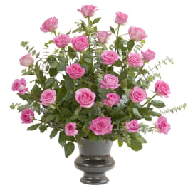 Tall arrangement of pink roses in a dark pedestal vase