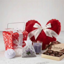 Romantic gift set with red heart pillow, candle, chocolates, and heart-print gift box
