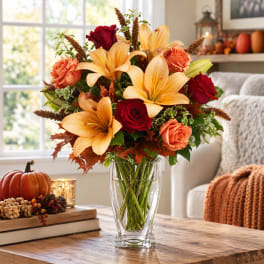 Autumn bouquet of lilies and roses in a clear glass vase