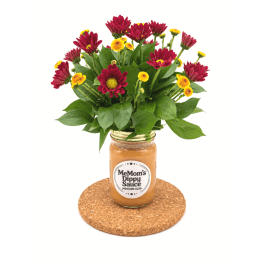 Red and yellow flowers in a jar vase on a cork coaster