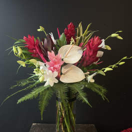 Tropical bouquet with white anthuriums and red ginger in a glass vase