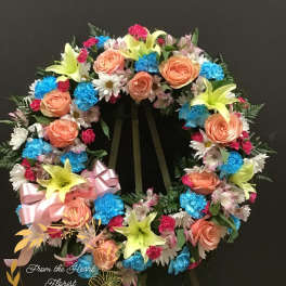 Colorful floral wreath with roses, lilies, and daisies on a stand