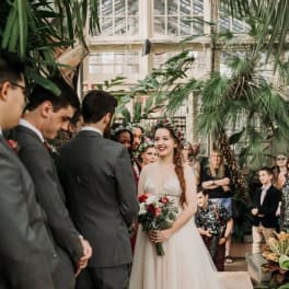 Bride holding a red and white bouquet at an indoor wedding ceremony