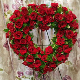Heart-shaped wreath of red roses on a metal stand