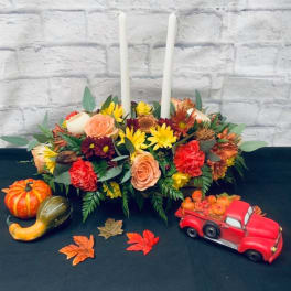Autumn floral centerpiece with two white taper candles and pumpkins