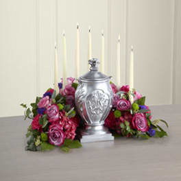 Pink and purple rose arrangement around a silver urn with tall white candles