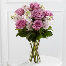 Pink roses and white blossoms arranged in a clear glass vase