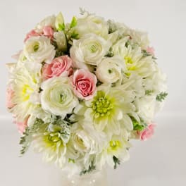 Round bouquet of white and pink flowers in a clear vase