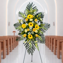 Yellow and white floral standing spray on an easel in a church aisle