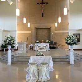 Church altar with white and blue floral arrangements on pedestals