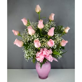 Pink roses arranged in a pink vase with a ribbon bow