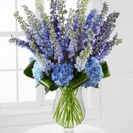 Blue and lavender flower arrangement in a clear glass vase