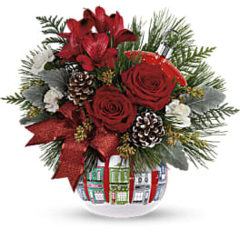 Red roses and lilies in a decorated glass vase with pinecones