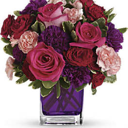 Bouquet of pink, red, and purple roses in a purple glass vase