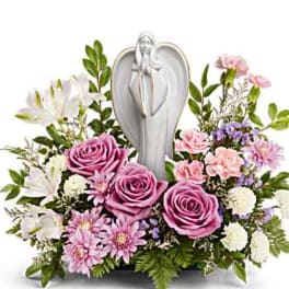 Pink roses and white flowers arranged around a silver angel figurine