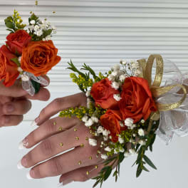 Orange rose corsage and boutonniere with white baby's breath and gold ribbon