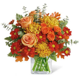 Autumn bouquet of orange roses and red-yellow mums in a clear glass vase