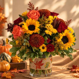 Autumn bouquet of sunflowers, roses, and mums in a glass vase