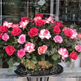 Large arrangement of pink and red roses in a gold bowl