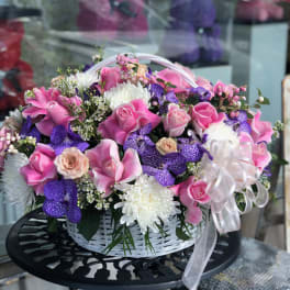 Pink and purple flower basket with roses and orchids in a white basket