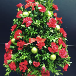 Red floral tree arrangement with green ornaments and ribbon