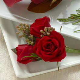 Three red roses with small berry accents on a white tray