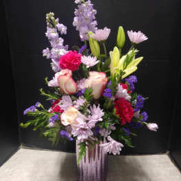 Mixed bouquet in a purple vase with pink, lavender, and yellow flowers