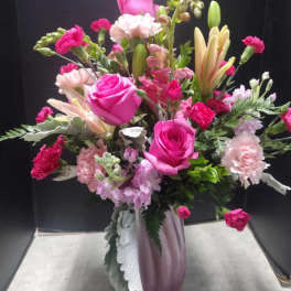 Pink rose and lily bouquet in a purple vase