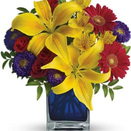 Bouquet of yellow lilies, red roses, and purple daisies in a blue vase