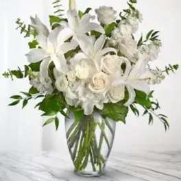 White lilies and roses arranged in a clear glass vase