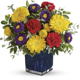 Colorful bouquet of yellow, red, and purple flowers in a blue glass vase