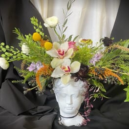 Floral arrangement on a white bust with white orchids and mixed blooms