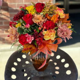 Autumn bouquet of red roses, chrysanthemums, and carnations in a glass vase