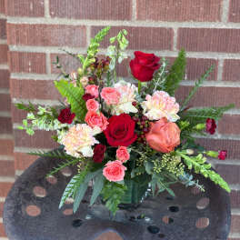 Mixed bouquet of red and pink roses with carnations in a glass vase