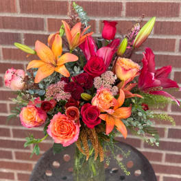 Bouquet of orange lilies and red roses in a glass vase