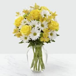 Yellow roses and white daisies in a clear glass vase