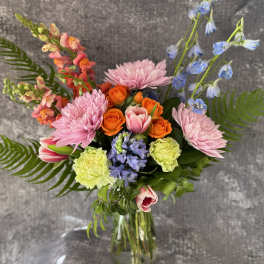 Mixed bouquet in a glass vase with pink, orange, and blue flowers