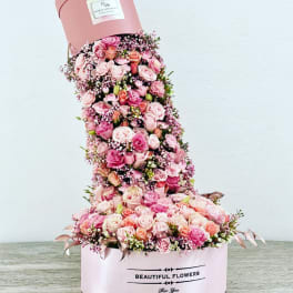 Tall pink hatbox arrangement of roses and baby’s breath
