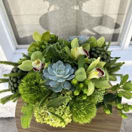 Green floral arrangement with orchids, succulents, and hydrangea on a round table