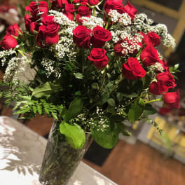 Red roses arranged in a clear glass vase with white baby's breath