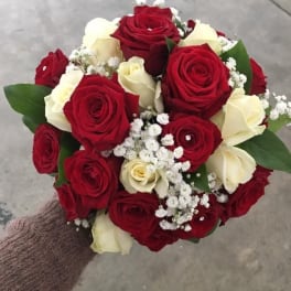 Handheld bouquet of red and white roses with baby's breath