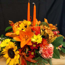 Autumn bouquet with sunflowers, lilies, carnations, and two orange candles